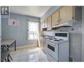 A kitchen with a white stove top oven and a window with blinds.
