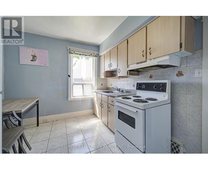A kitchen with a white stove top oven and a window with blinds.