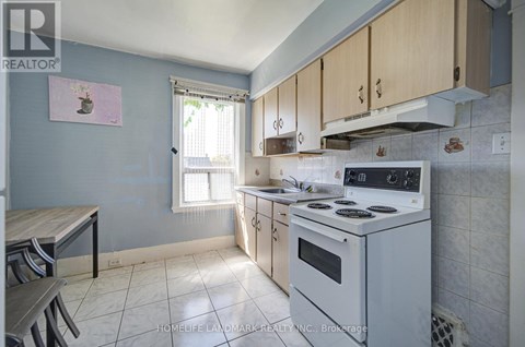 A kitchen with a white stove top oven and a window with blinds.