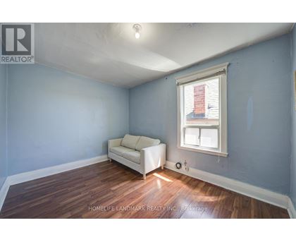 A room with a white couch and a window with blinds.