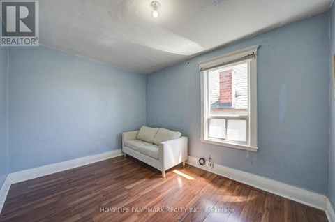 A room with a white couch and a window with blinds.
