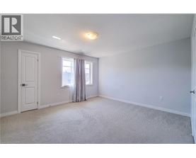 A bedroom with a carpeted floor and a window with curtains.