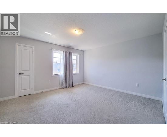 A bedroom with a carpeted floor and a window with curtains.