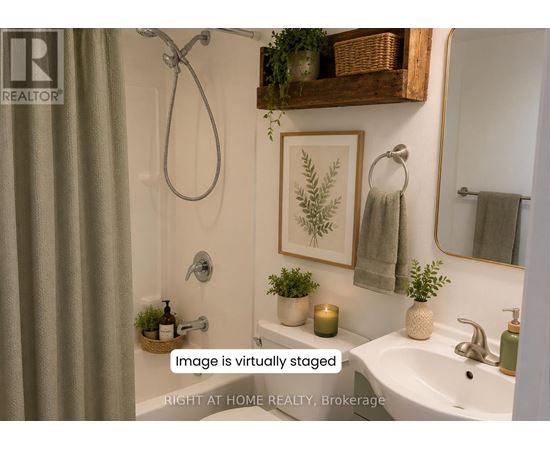 A bathroom with a white sink, a mirror, a plant, and a candle.