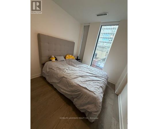 A bedroom with a large bed and a window overlooking a cityscape.