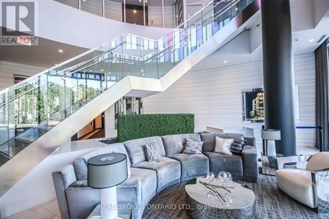 A living room with a grey couch and a glass table.