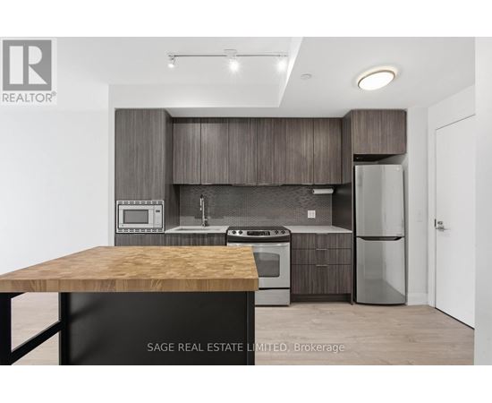 A modern kitchen with a wooden table and stainless steel appliances.