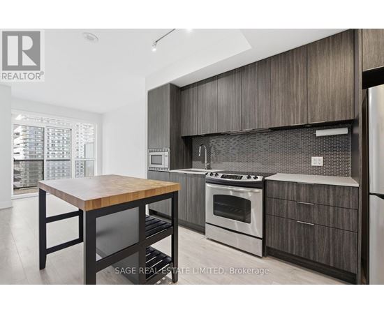 A modern kitchen with a wooden table and stainless steel appliances.