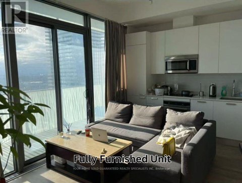 A fully furnished living room with a couch, coffee table, and a view of the city.