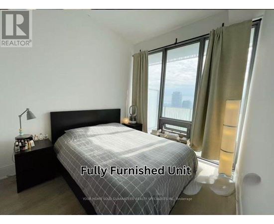 A bedroom with a large bed and a window with curtains.