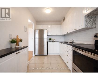 A kitchen with white cabinets and a stainless steel refrigerator.