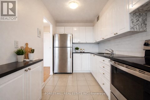 A kitchen with white cabinets and a stainless steel refrigerator.