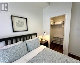 A bedroom with a bed, a nightstand with a lamp, and a framed picture on the wall.