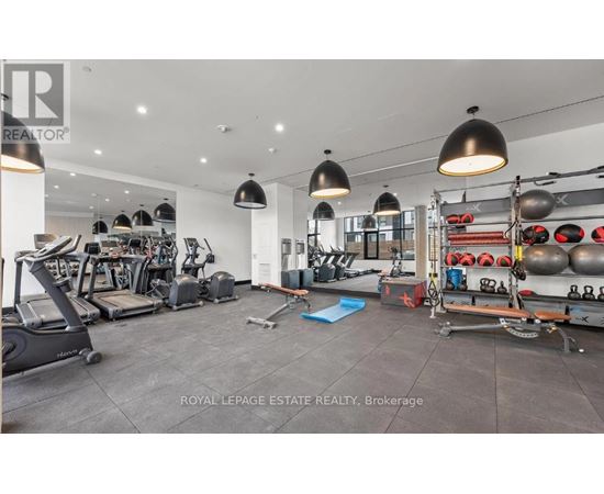 A spacious gym with various exercise equipment and a blue mat on the floor.