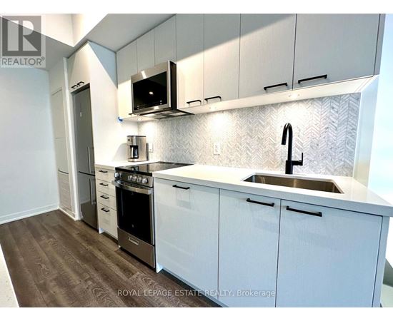 A kitchen with white cabinets and a stainless steel sink.