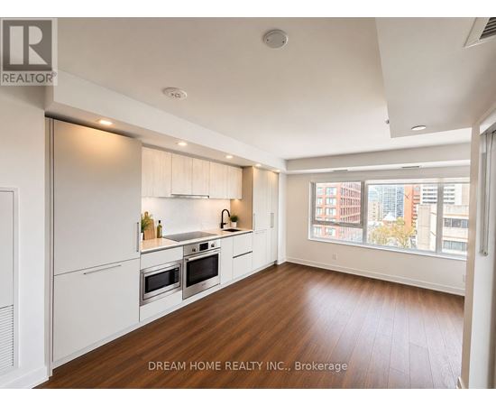 A modern kitchen with white appliances and wooden floors.