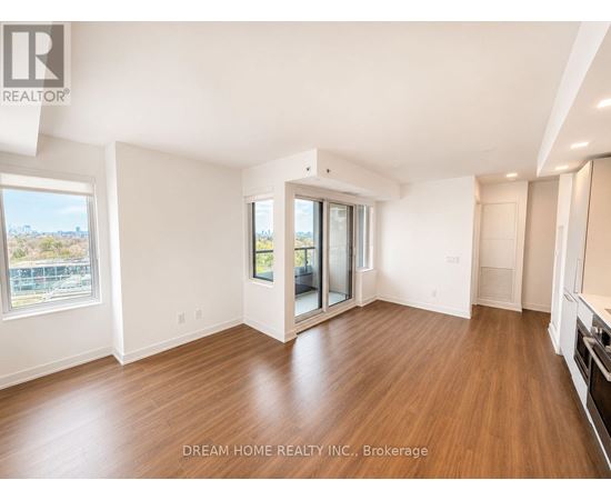 A spacious room with wooden floors and a large window overlooking a cityscape.