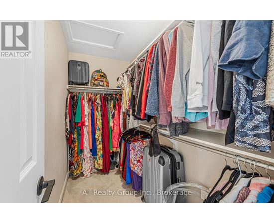 A cluttered closet with clothes and a suitcase.
