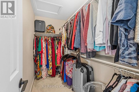 A cluttered closet with clothes and a suitcase.