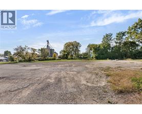 A large, empty field with a grain silo in the distance.