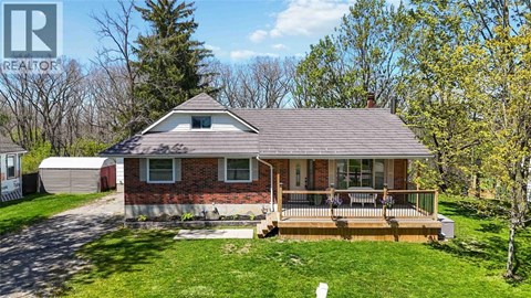 A house with a red brick exterior and a brown roof with a deck in front.