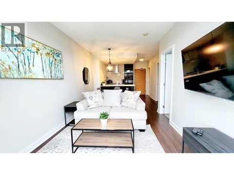 A living room with a white couch and a painting on the wall.