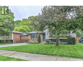 A house with a green lawn and trees in front.