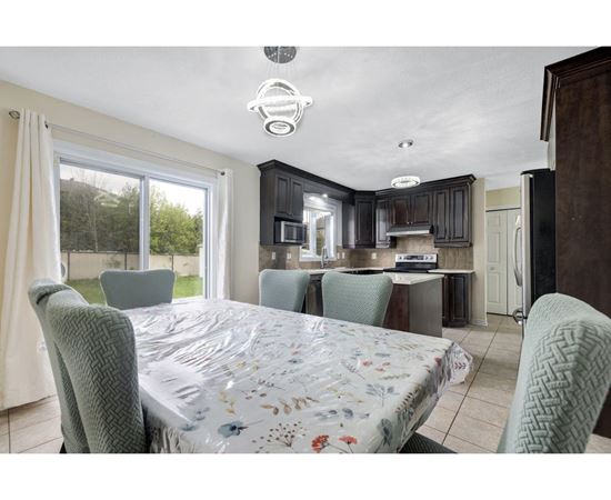 A bedroom with a large bed and a kitchen area in the background.
