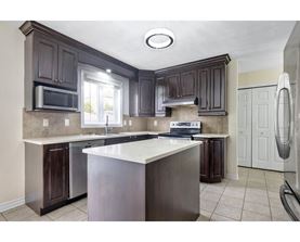 A kitchen with dark brown cabinets and a white island.