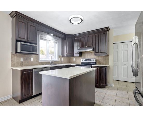 A kitchen with dark brown cabinets and a white island.