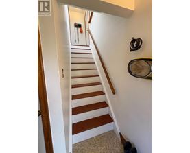 A staircase with a white wall and a black railing.