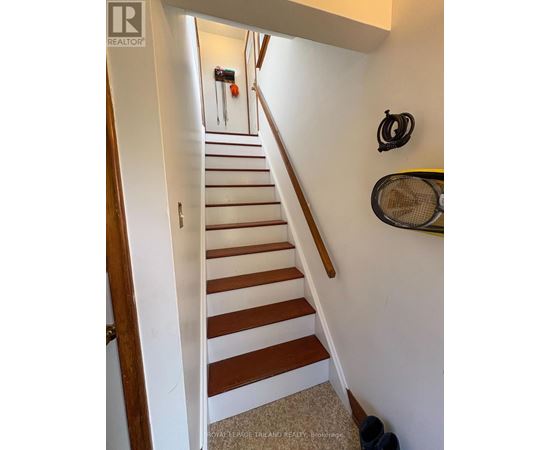 A staircase with a white wall and a black railing.
