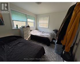 A bedroom with two beds and a window with blinds.