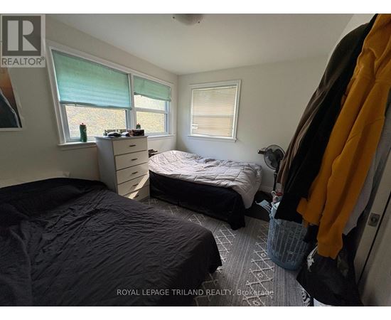 A bedroom with two beds and a window with blinds.