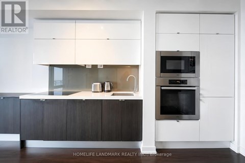 A modern kitchen with dark wood cabinets and white appliances.