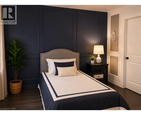 A bedroom with a large bed and a nightstand with a lamp.
