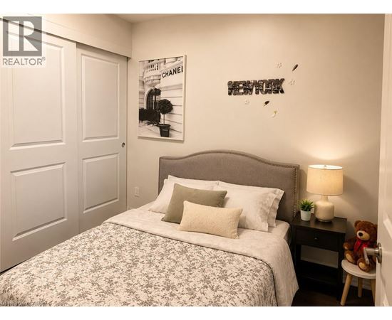 A bedroom with a bed, a teddy bear, and a lamp.