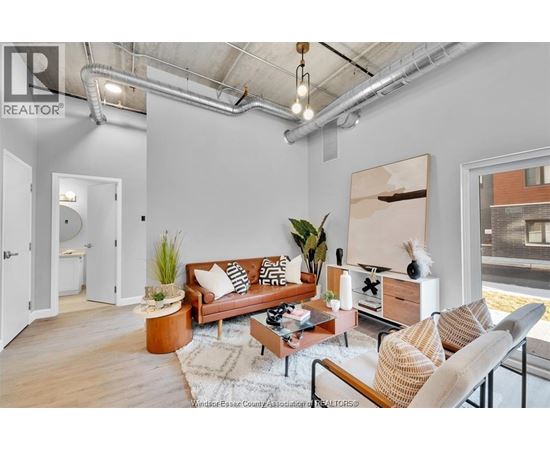 A living room with a brown couch, a coffee table, and a painting on the wall.