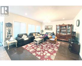 A living room with a black couch, a white coffee table, and a red floral rug.