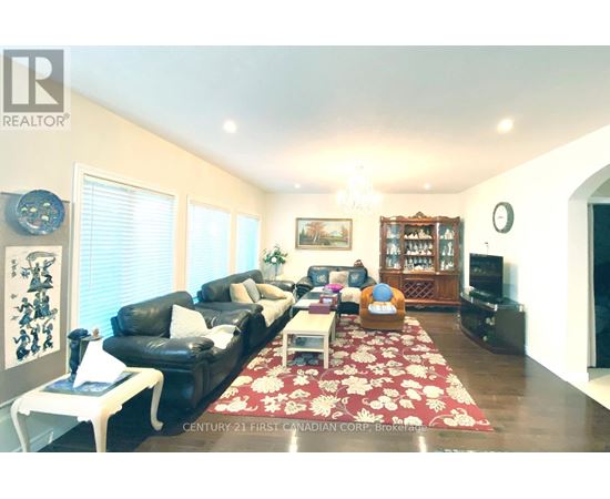 A living room with a black leather couch and a red floral rug.
