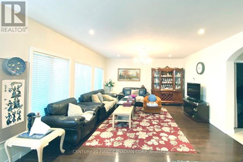 A living room with a black leather couch and a red floral rug.