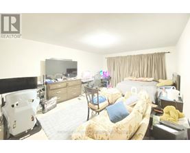 A bedroom with a bed, a chair, a dresser, and a television.