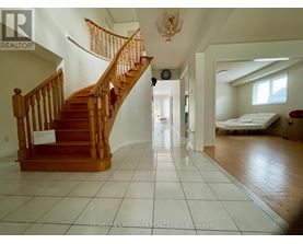 A large open room with a staircase and a bed in the background.