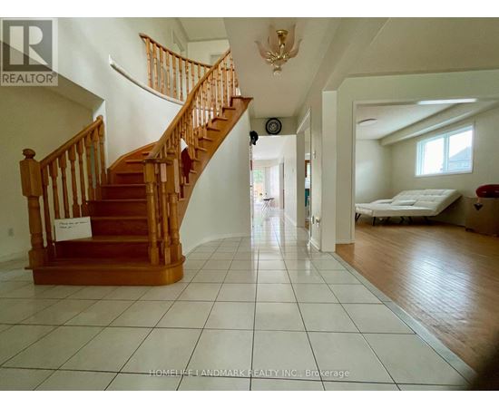 A large open room with a staircase and a bed in the background.