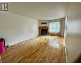 A room with wooden flooring and a fireplace in the corner.
