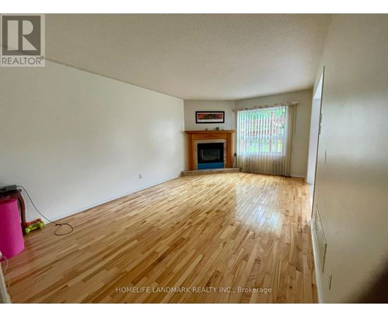 A room with wooden flooring and a fireplace in the corner.