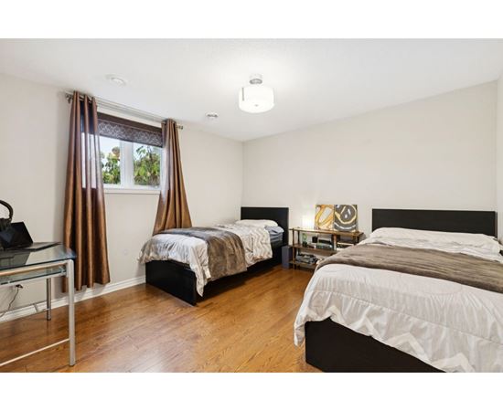 A bedroom with two beds and a window with brown curtains.