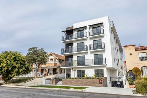 A modern white apartment building with black railings and balconies.