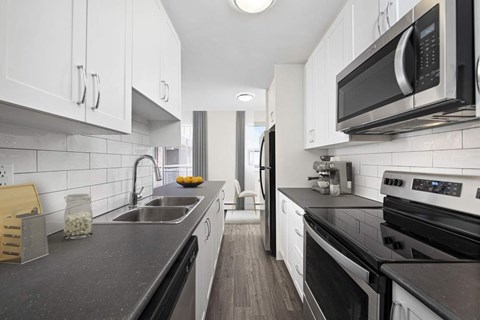 A modern kitchen with black countertops and white cabinets.