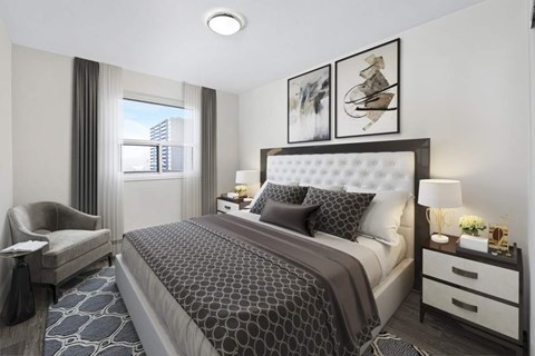 A well-lit bedroom with a large bed and a chair.